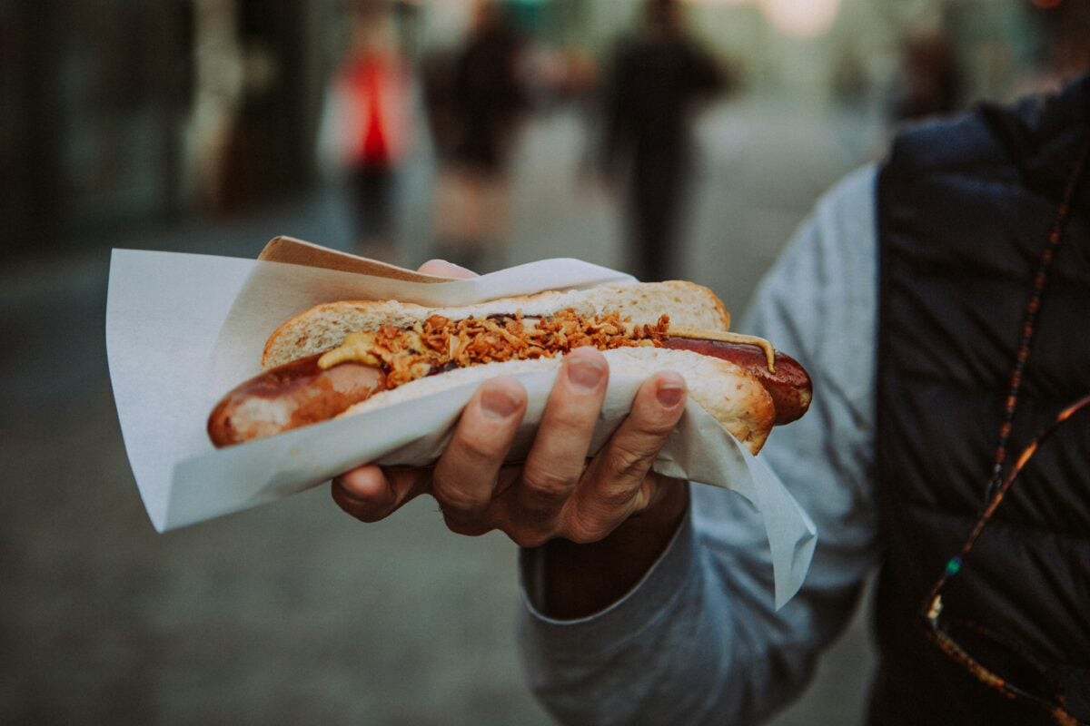 A person holding a hot dog in their hand.