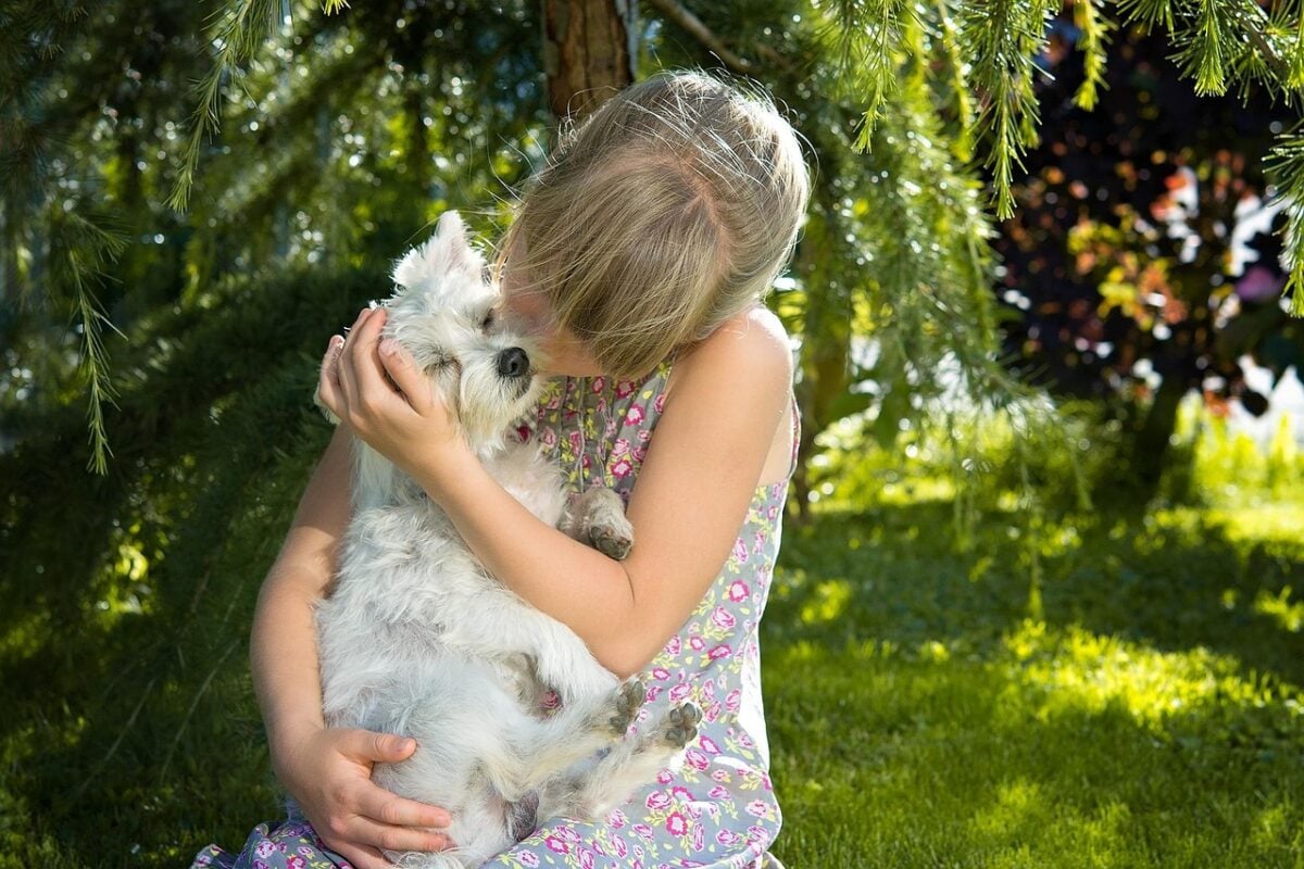 A child cuddling their dog outdoors.