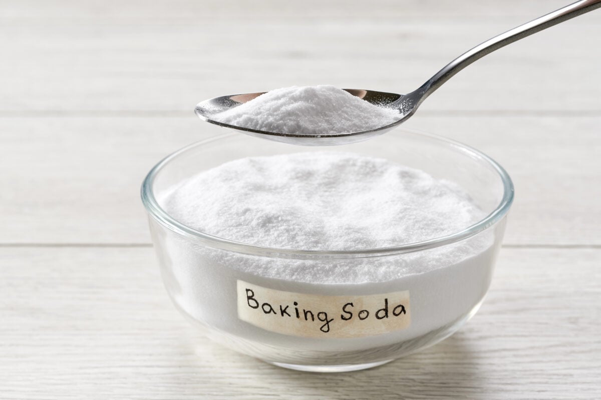 Bowl with baking soda on white wooden table.