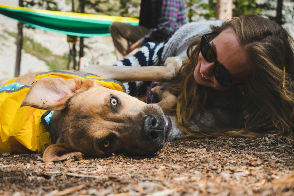 Woman lying on leaves with her Pitbull looking goofy.
