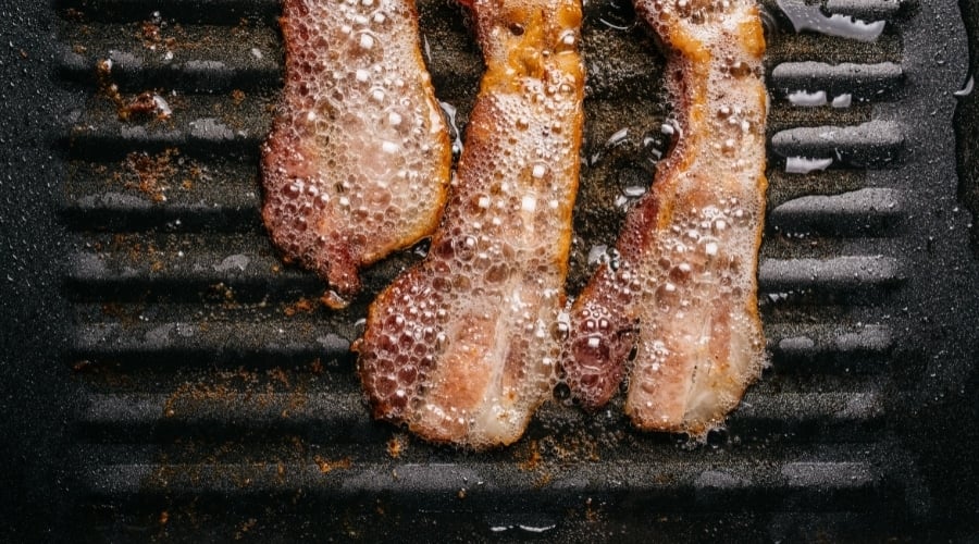 Bacon with grease in frying pan.