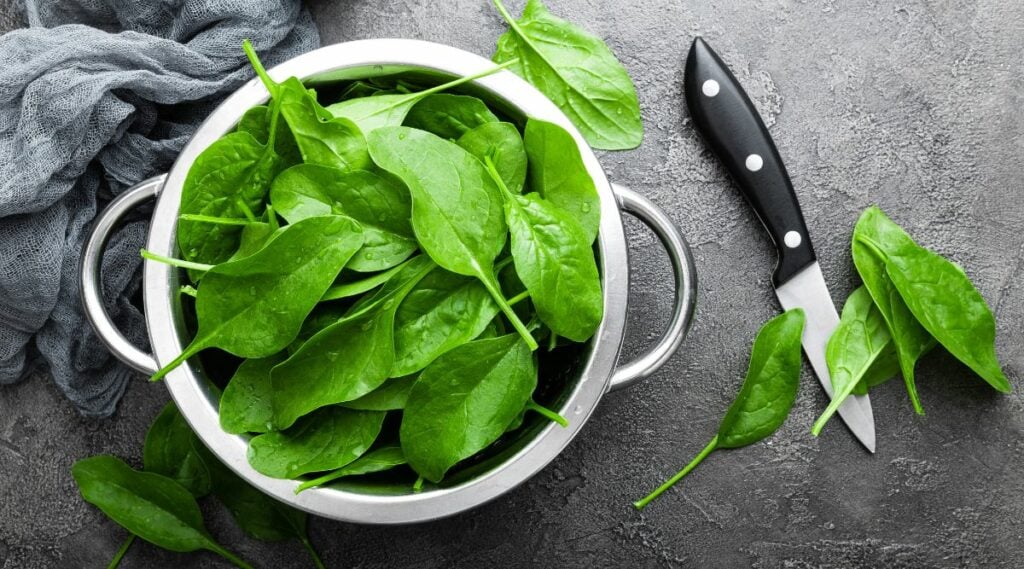 Bowl of spinach with knife overhead shot