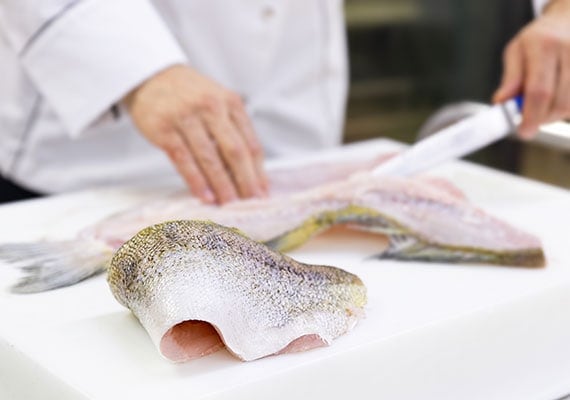 Chef removing skin from cod to be used in fish skin dog treats