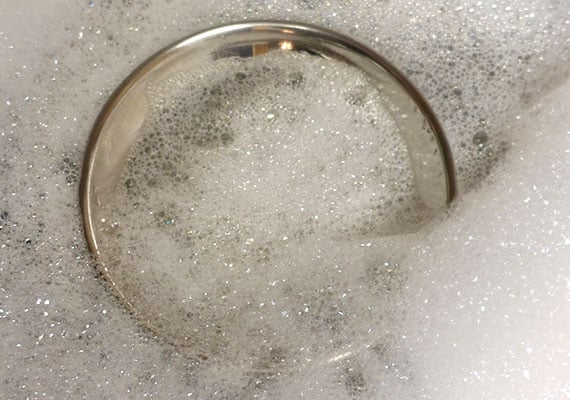 Cleaning a stainless steel dog bowl in warm soapy water