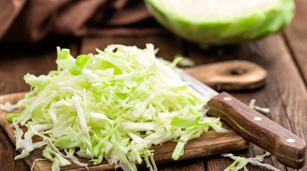 Cutting board with chopped cabbage.