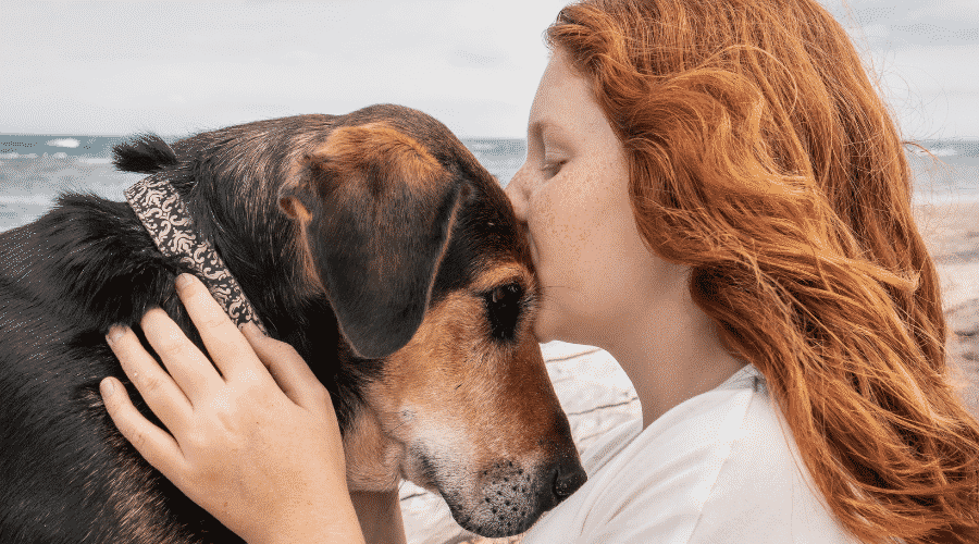 Young redhead girl kissing head of loyal Huntaway pet dog