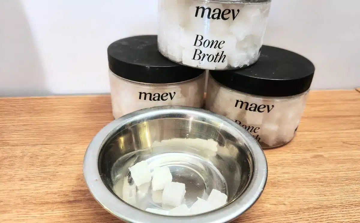 Maev bone broth containers stacked next to bowl of cubes