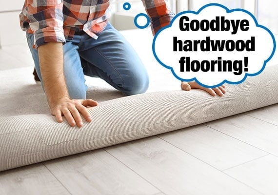 Man installing new flooring as he rolls out carpet to cover up slippery hardwood floor