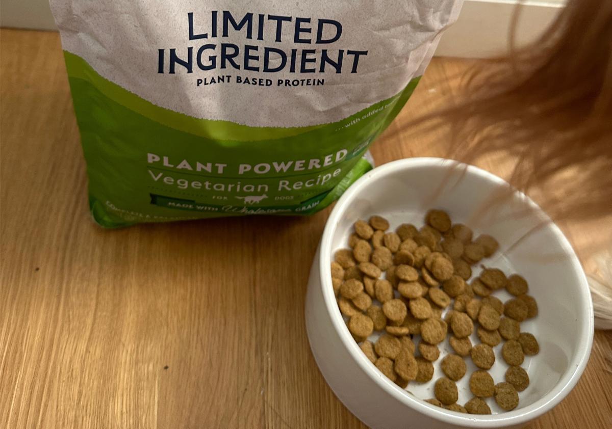 Natural Balance dog food bag and food in a bowl on the ground.