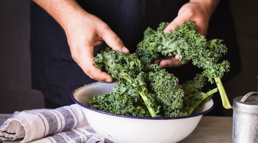 Person separating kale leaves in bowl