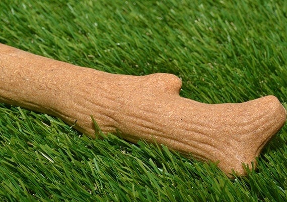 Petstages Dogwood wooden chew toy sitting in grass