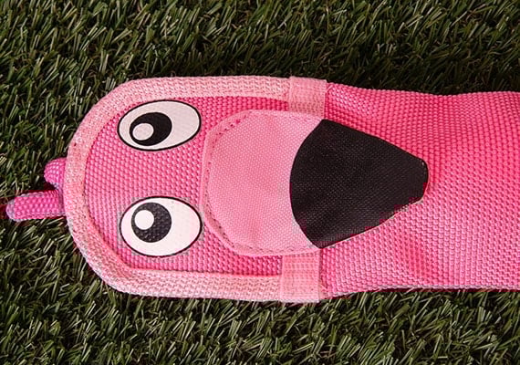 Pink flamingo fire hose dog toy sitting on grass