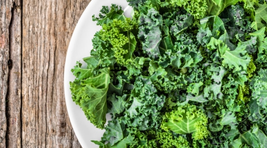 Raw kale on plate on table