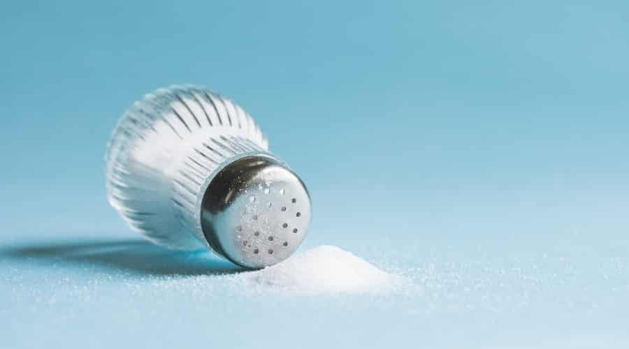 Salt shaker spilling over on a blue background.