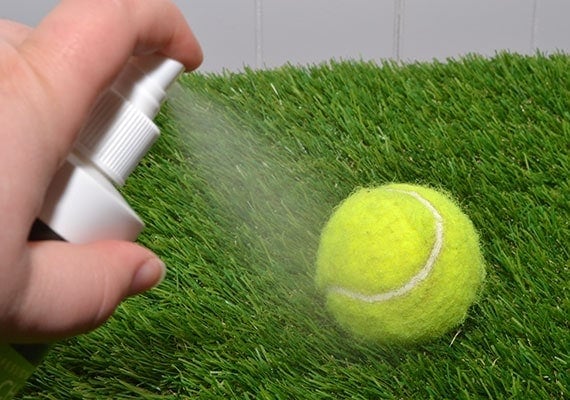 Spraying a tennis ball with anti-chew spray