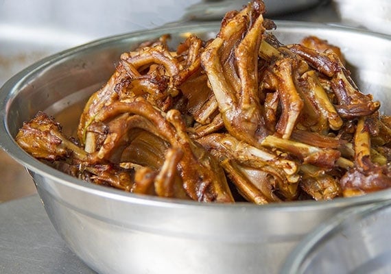 Stainless steel bowl filled with dehydrated duck feet dog chews