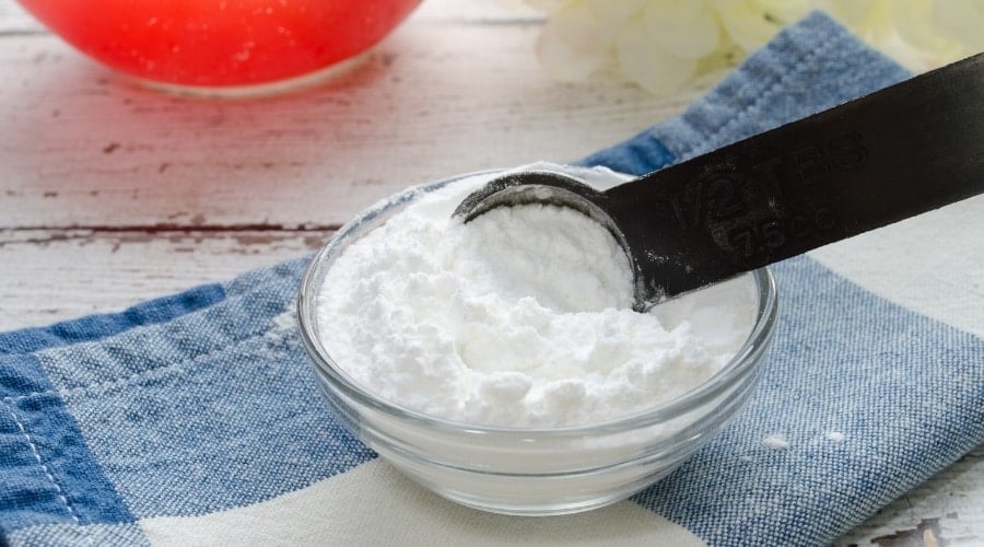 Small bowl of baking powder with a scoop.