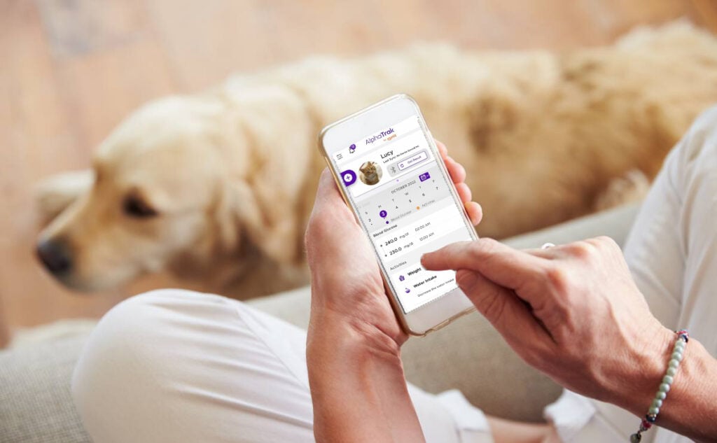 Woman with dog using AlphaTRAK 3 Pet Blood Glucose Monitoring app.