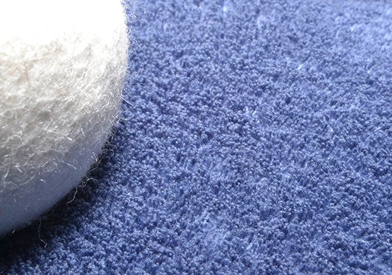 Wool dryer ball successfully removing dog hair from blue towel in laundry