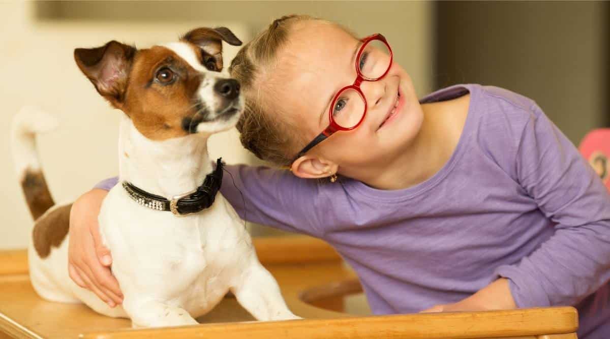 Young girl with glasses hugging dog