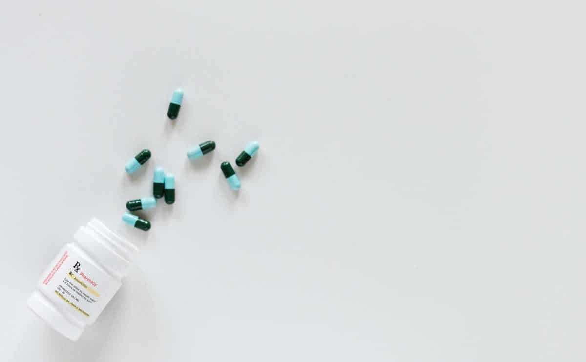 What Are The Best Pain Meds For Dogs? Bottle of pain meds for dogs on ground with pills spilling out.