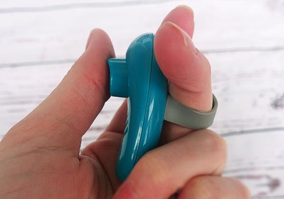 Dog training clicker connected to finger by finger strap