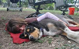 Girl hugging dog on the ground