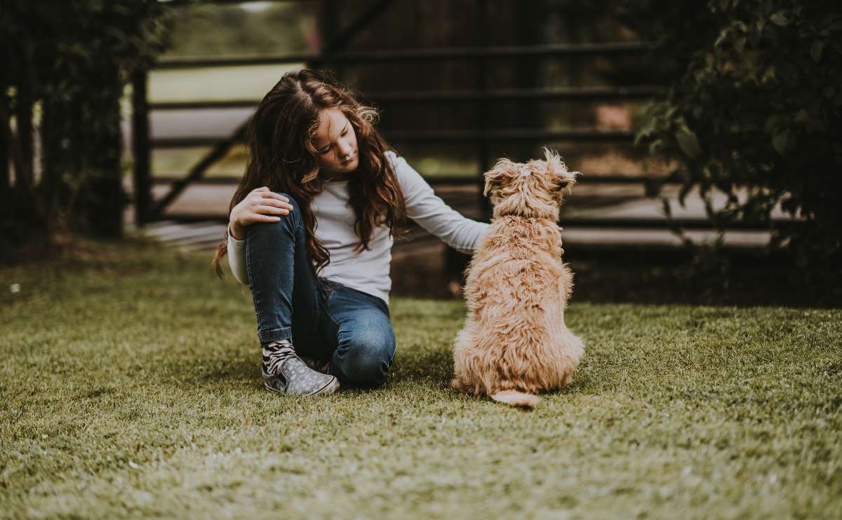 Health Benefits Of Having A Dog girl outside petting dog sitting on the ground