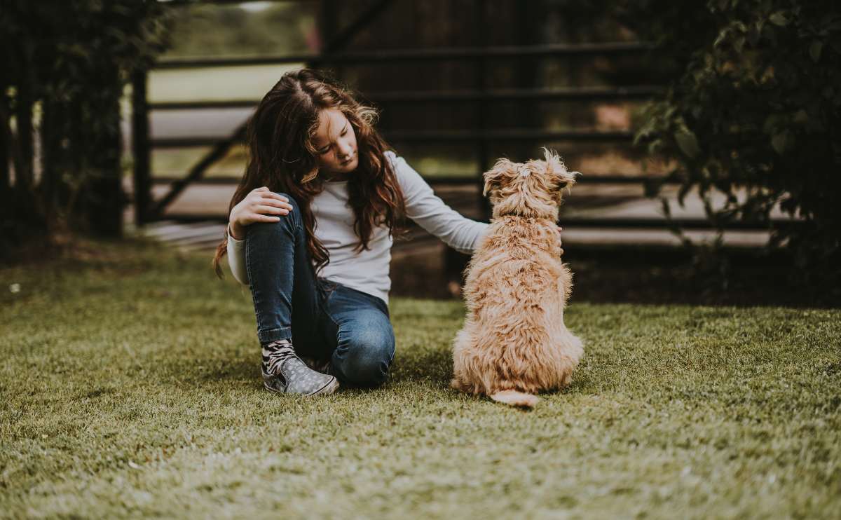 girl outside petting dog sitting on the ground jpg