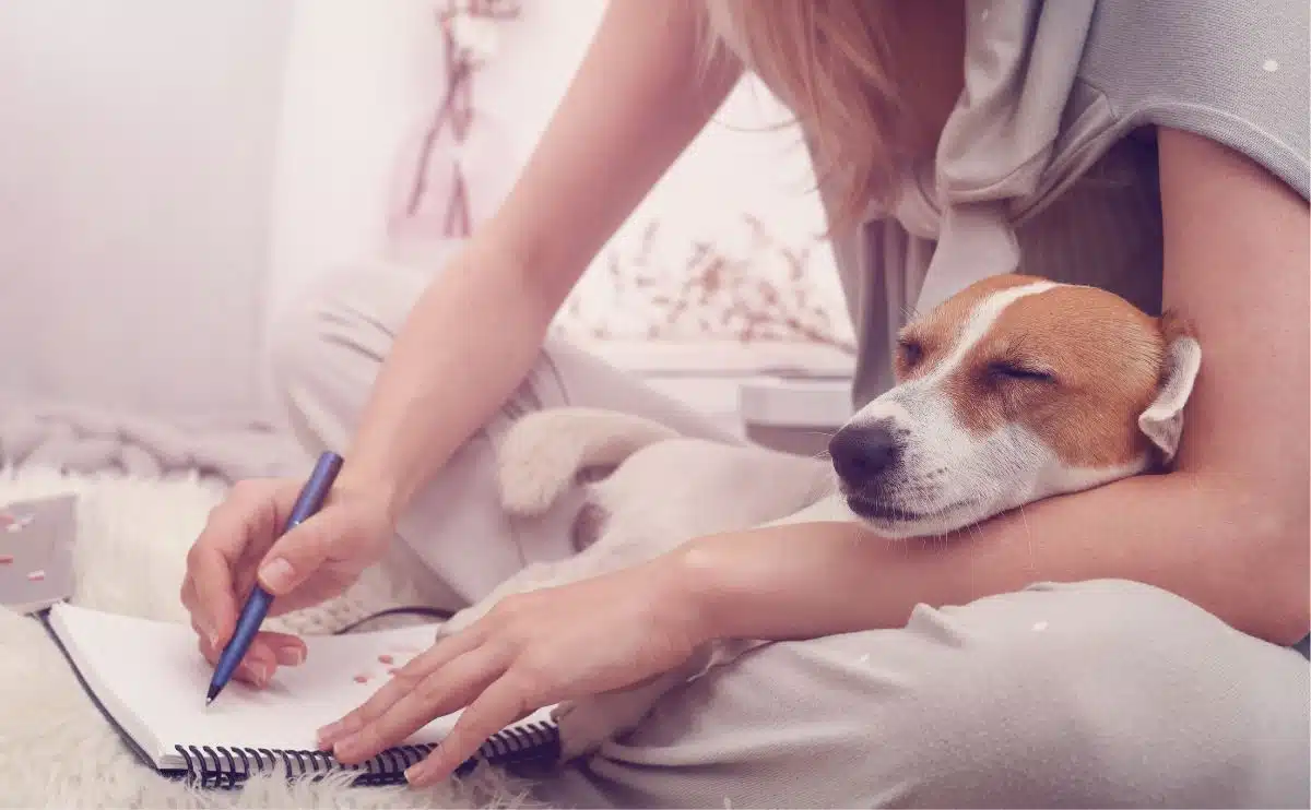 girl sitting with puppy in her arms writing a checklist