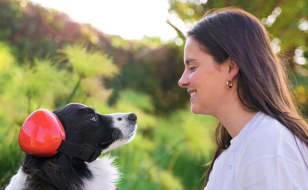Girl with dog wearing noise cancelling headphones outside.