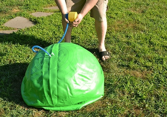 Person inflating green herding ball.