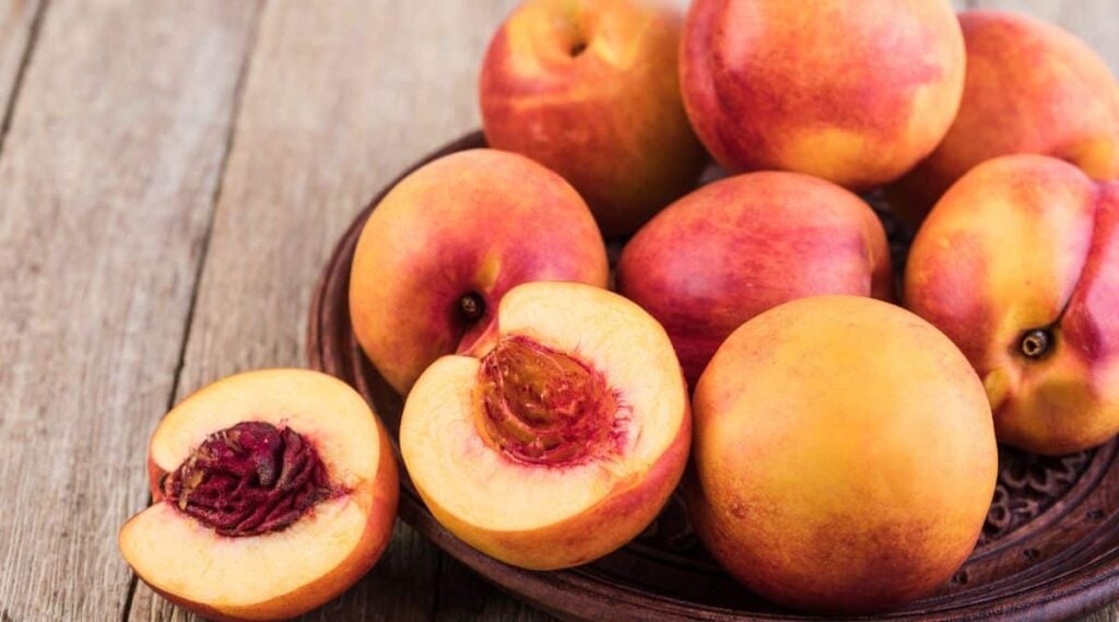 nectarine sliced open next to a bunch of nectarines
