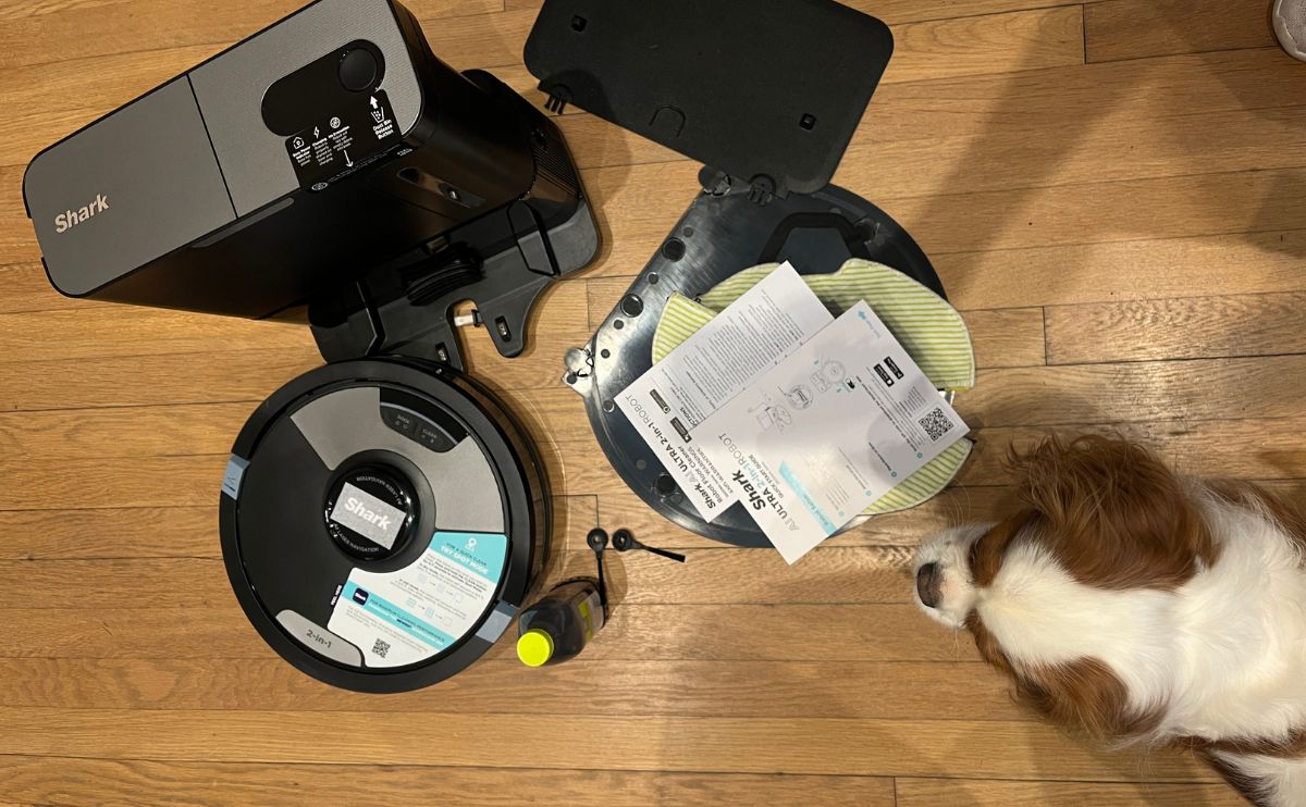 Dog next to personal experience using shark robot vacuum overhead shot.