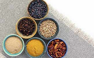 Spices and peppercorns in small containers on counter