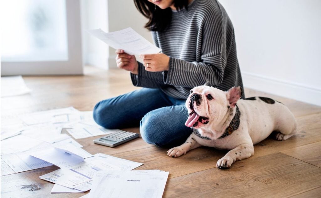 Woman doing taxes sitting on the floor with dog.